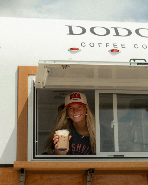 DODO Coffee operator holding a drink inside a mobile coffee trailer