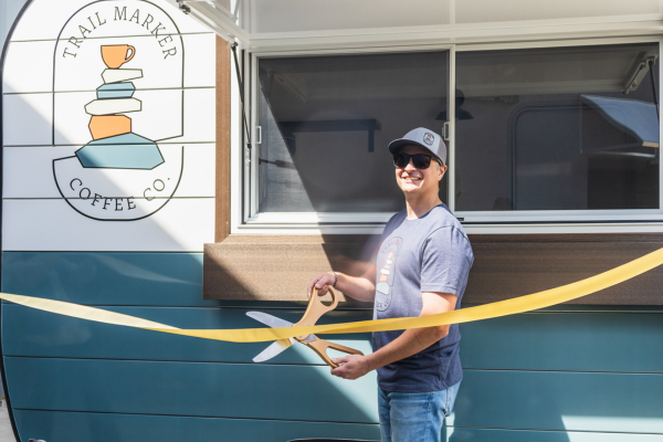 Trail Marker Coffee Co. owner cutting a ribbon beside the finished trailer
